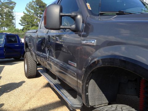 2006 Ford F-350 - The side of a dark gray Ford F-350 pickup truck is shown, with damage visible on the rear door and fender.