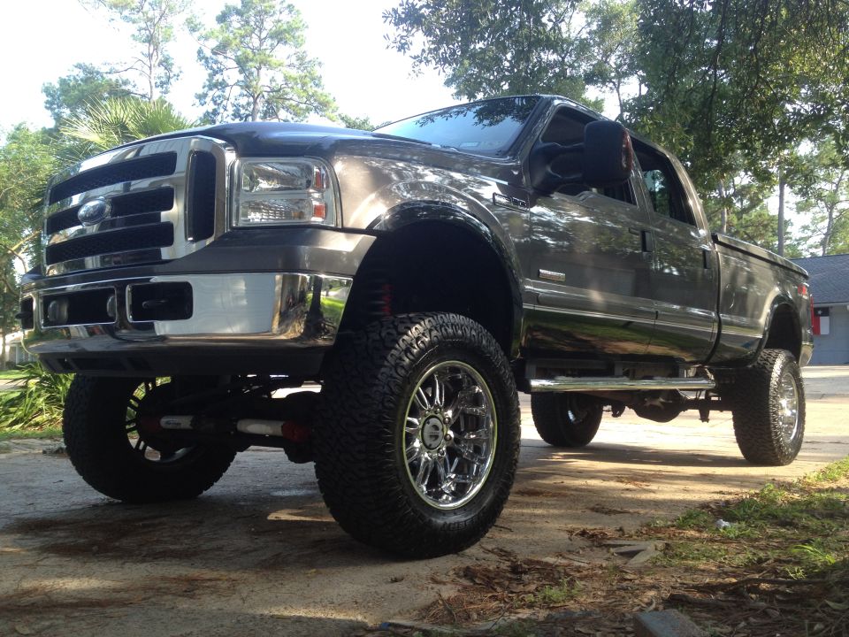 Dark gray lifted Ford F-350 Super Duty pickup truck with chrome wheels and side steps