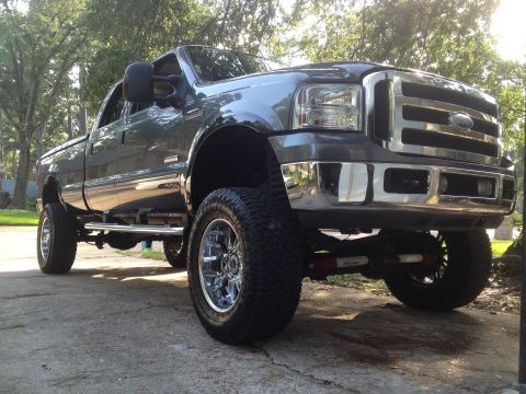 2006 Ford F-350 - This lifted Ford Super Duty pickup truck is shown from a low front quarter angle, highlighting its large tires and chrome accents.