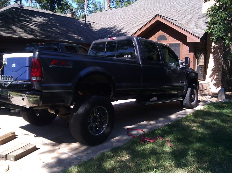 Dark gray Ford F-350 pickup truck parked in driveway, another truck behind it