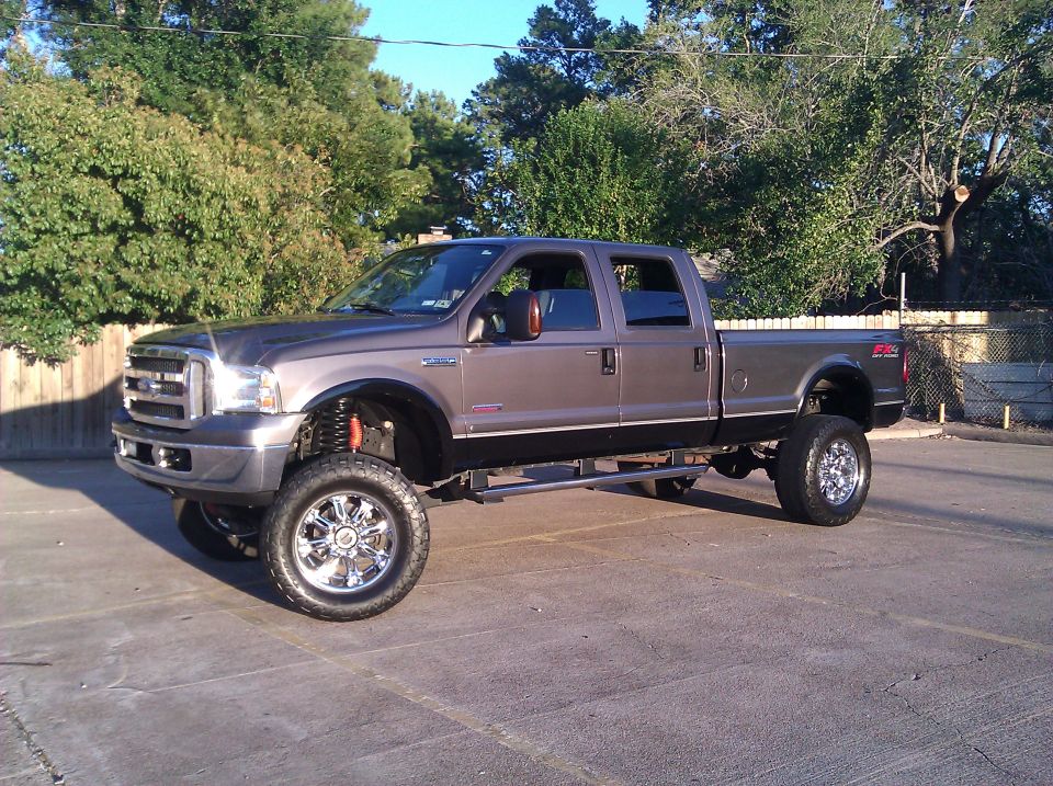 Gray lifted pickup truck with chrome wheels and black trim, seen from a 3/4 front angle