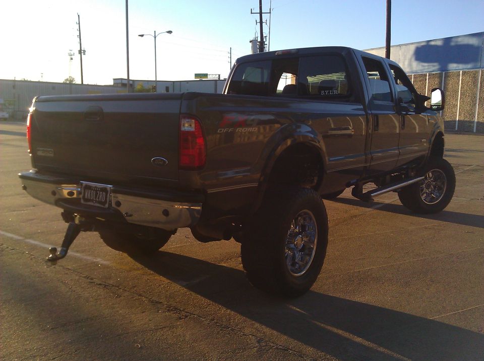 Lifted dark gray Ford Super Duty pickup truck, rear view, with "OFF ROAD" decal on fender