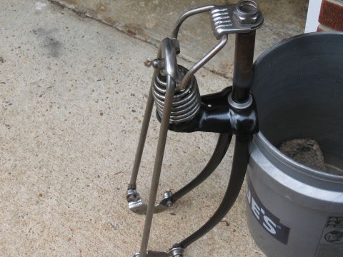 1994 Ford Bronco - A close-up view of a custom bicycle fork with visible springs, next to a bucket.