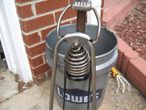 1994 Ford Bronco - A close-up view of a spring mechanism is shown in front of a bucket and brick wall.