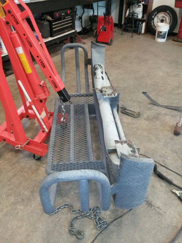 Engine hoist next to a detached truck bumper with a chain