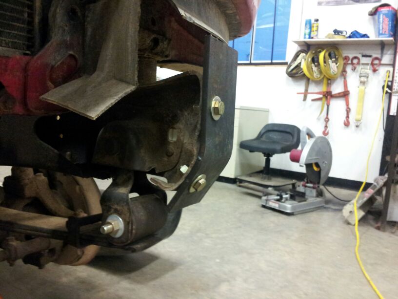 Close-up of a truck's front suspension and frame with a metal bracket bolted on