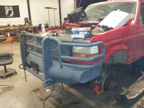 1995 Ford F-150 - Front view of a red Ford truck undergoing repairs, showing a heavy-duty bumper and grille guard.