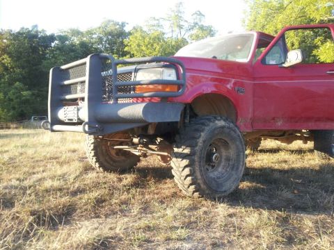 1995 Ford F-150 - A red Ford F-250 truck is shown from the front-three-quarter view, equipped with a heavy-duty brush guard and large tires.