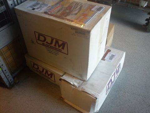 1997 Chevrolet Silverado 1500 - Several boxes labeled DJM Suspension are stacked in a storage area. A Summit Racing catalog is visible on the top box.