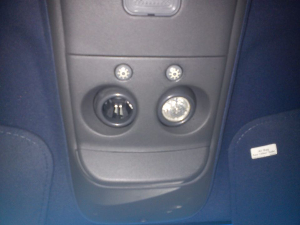 Overhead console with power outlet, light, and two buttons. Blue upholstery visible