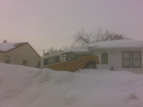 1966 Ford Bronco - Yellow 1966 Ford Bronco stuck in deep snow beside a residential building.