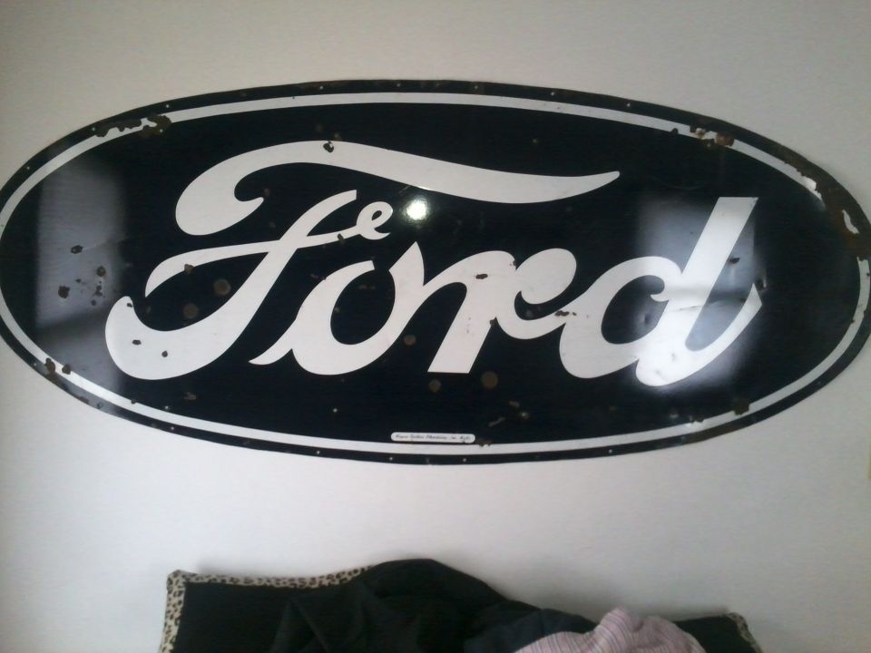 Large vintage black and white porcelain oval Ford sign mounted on a wall