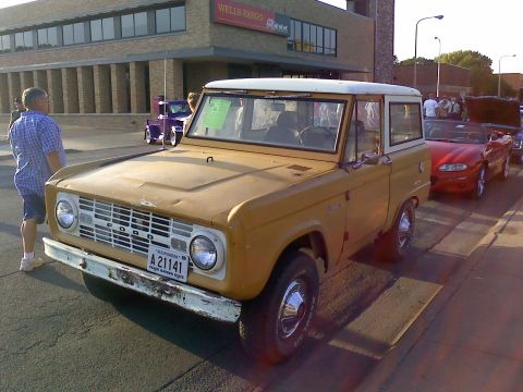 1966 Ford Bronco - A 1966 Ford Bronco is parked on a street with other vehicles, including a red convertible.