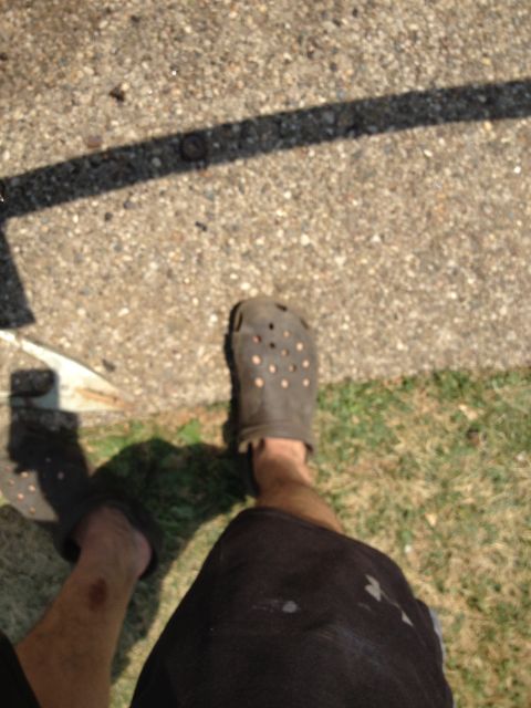 1986 Ford Bronco - Photo shows a person's legs and feet wearing dark Crocs, with shadows cast on concrete and grass.