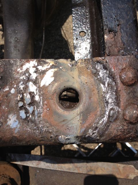 1986 Ford Bronco - Rusted vehicle frame section shows signs of repair with welding and a central hole.