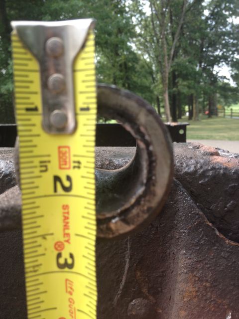 1986 Ford Bronco - A tape measure is shown next to a metal loop, indicating its size against a rusty background.