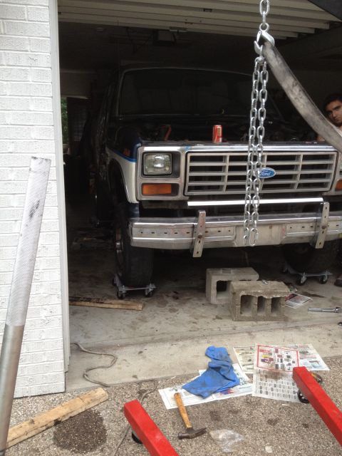 1986 Ford Bronco - A Ford Bronco, likely from the early 1980s, is undergoing repairs in a garage, suspended by a hoist.