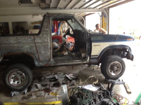 1986 Ford Bronco - This 1986 Ford Bronco is undergoing a rebuild in a garage, with its doors removed and parts scattered around.