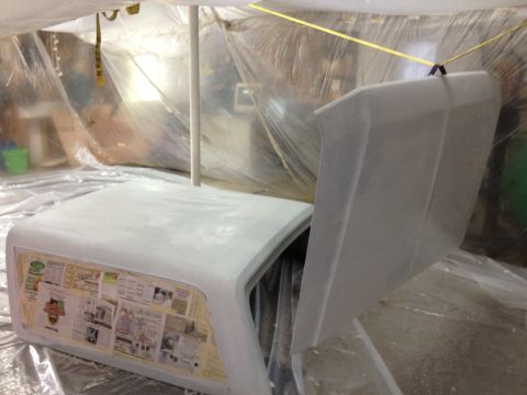 1986 Ford Bronco - Car hood and fender covered in primer, with newspaper lining the inside of the fender.