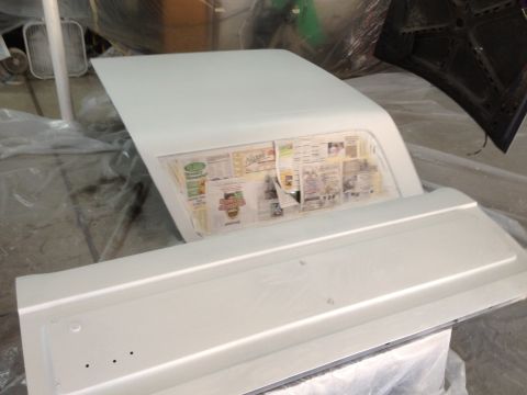 1986 Ford Bronco - Car parts are covered with newspaper inside a workshop, likely for painting or protection.