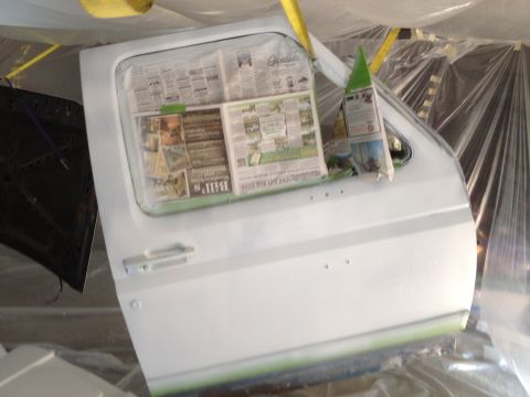 1986 Ford Bronco - A vehicle door is masked with newspaper and plastic for painting, with the hood open to the left.