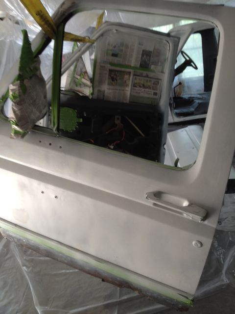 1986 Ford Bronco - Interior of a 1986 Ford Bronco being prepped for paint, with the door ajar and dashboard covered.