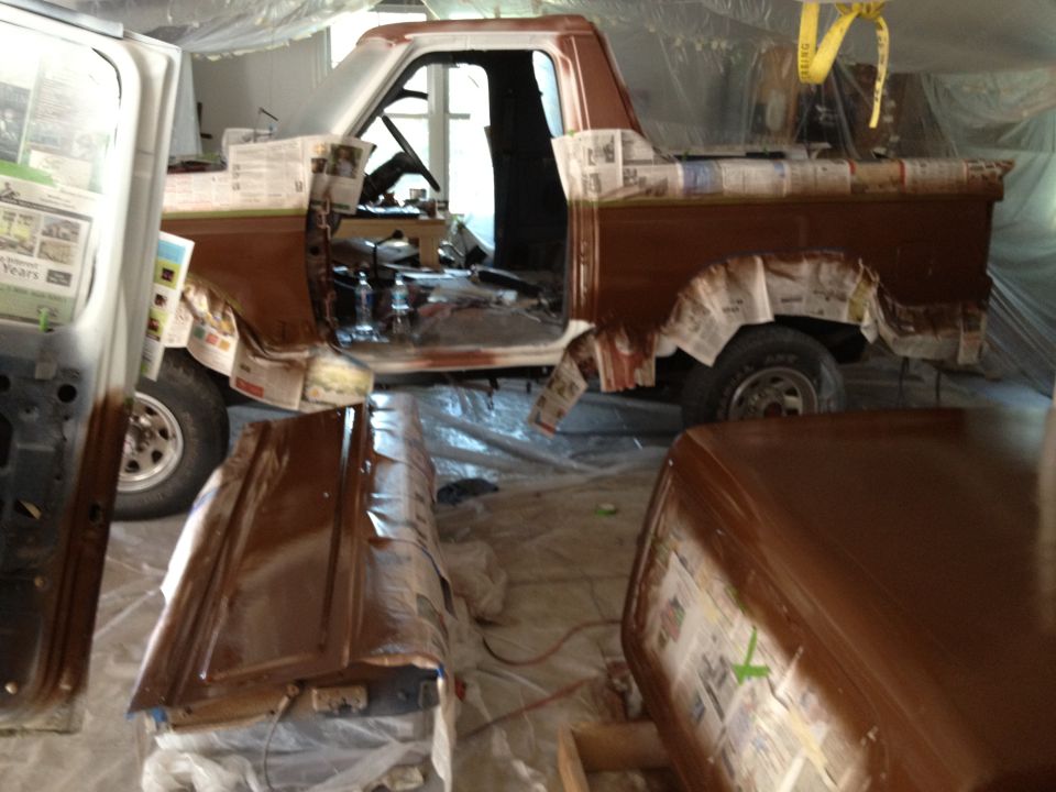 1986 Ford Bronco in garage, masked for paint. Side view shows brown paint and interior