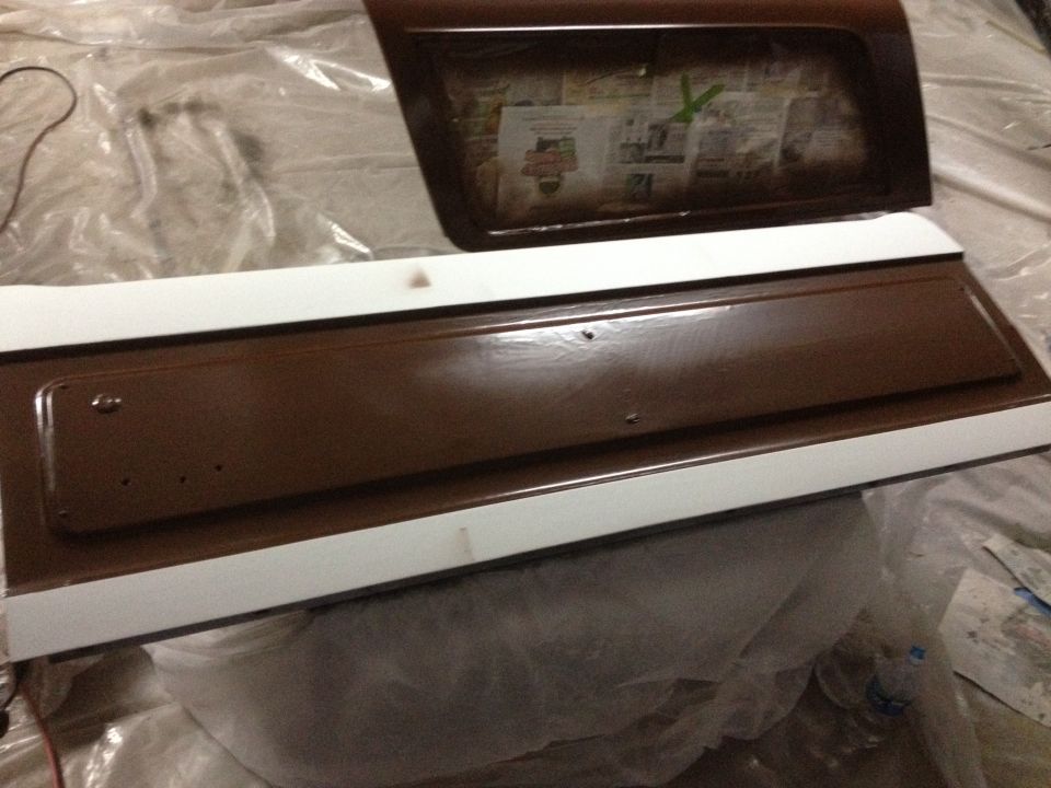 Brown and white tailgate and window frame, possibly for a Ford Bronco, covered in plastic sheeting