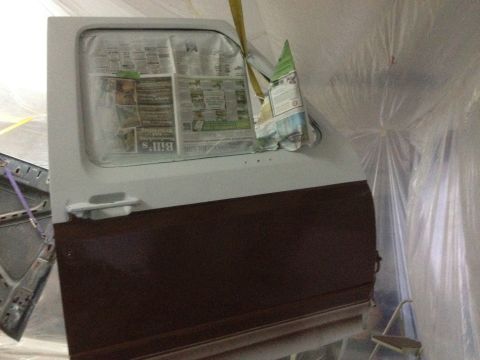 1986 Ford Bronco - Car door prepared for painting, with newspaper protecting the window area.