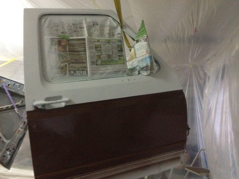 Car door covered in newspaper for painting, with a dark brown lower section