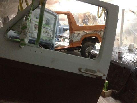 1986 Ford Bronco - Two vehicles are in a workshop, one is partially disassembled and covered in plastic sheeting.