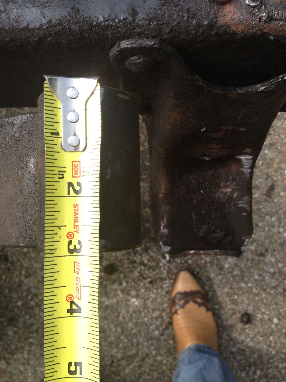 Measuring tape next to a rusty vehicle part