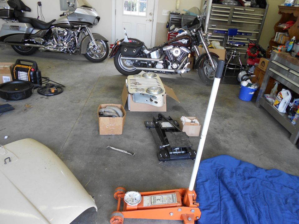 Two motorcycles parked in a garage with tools and car parts on the floor