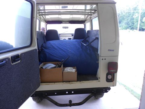 1986 Jeep Wagoneer - The rear cargo area of a Jeep CJ-8 Scrambler is visible, containing a blue sleeping bag and two cardboard boxes.