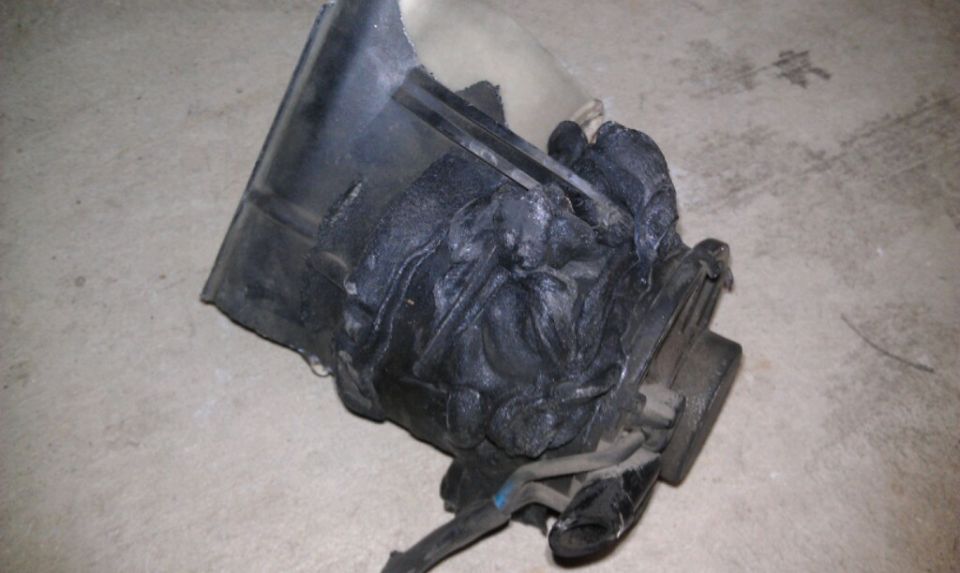 damaged black plastic vehicle part with melted or deformed sections