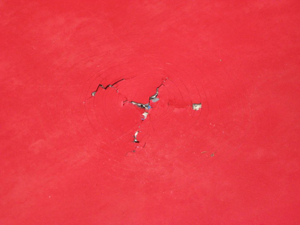 Red painted surface with cracked impact damage