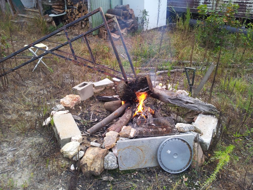 Campfire with logs and a grill, surrounded by cinder blocks and rocks