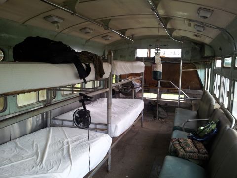 1986 Ford Bronco - Bus interior converted to sleeping quarters with bunk beds and seating. 'NO SMOKING' sign is visible.
