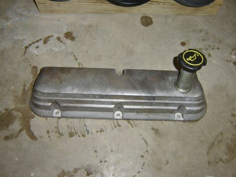 1984 Ford Mustang - An engine valve cover with an oil cap sits on a concrete surface, possibly in a garage or workshop.