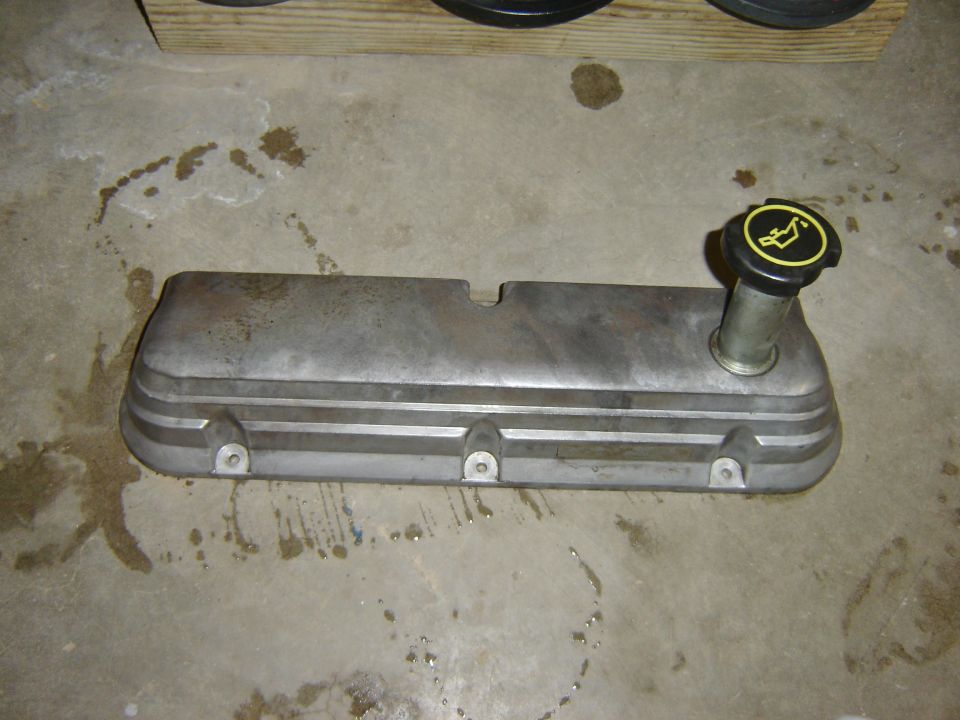 Aluminum engine valve cover with oil cap on concrete floor