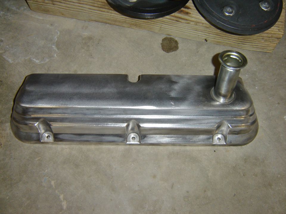 Metal valve cover with oil filler neck, resting on concrete floor