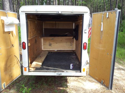 1986 Ford Bronco - The interior of a white cargo trailer is visible with its rear doors open.