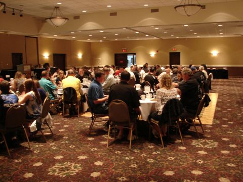 1992 Ford Taurus - Attendees gather for an event in a banquet hall, with the Supermotors logo visible in the corner.