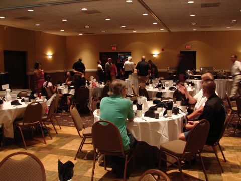 1992 Ford Taurus - A gathering of people are seated at round tables in a banquet hall, with some standing and mingling.