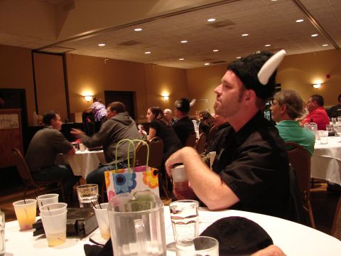 1992 Ford Taurus - Attendees at a banquet event, some wearing novelty hats, are seated at tables with drinks.