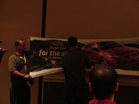 1992 Ford Taurus - A banner a red Ford Taurus with numerous signatures is displayed at an event.