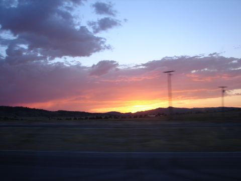 1992 Ford Taurus - A vibrant sunset paints the sky with hues of orange, pink, and purple over a distant mountain range.