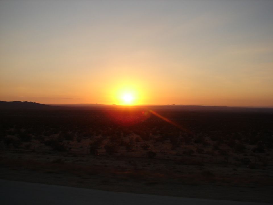 Desert landscape at sunset with sun low on horizon