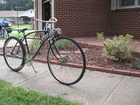1994 Ford Bronco - A vintage black bicycle with chrome handlebars and a headlight is parked on a sidewalk in front of a brick house.