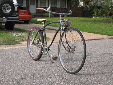 1994 Ford Bronco - A vintage bicycle sits on an asphalt road with a house and other vehicles in the background.